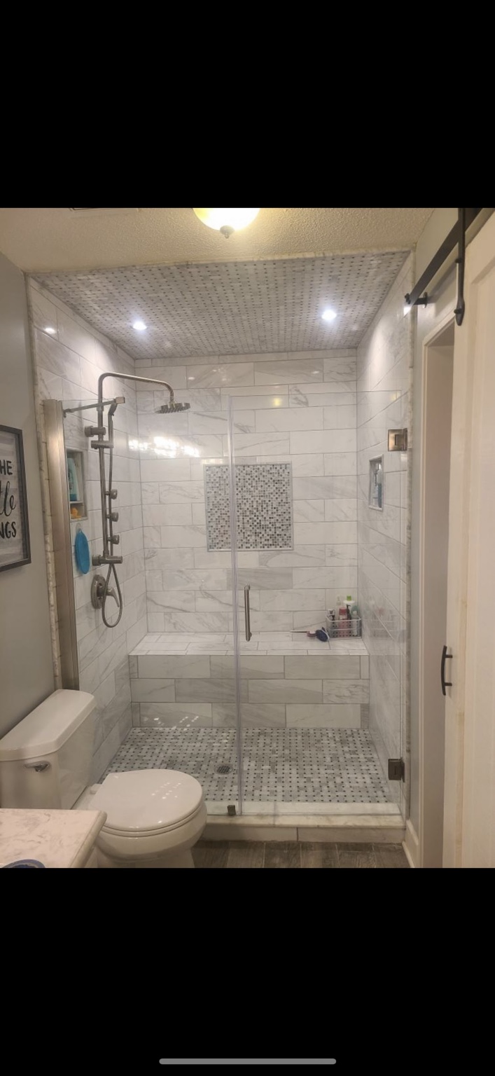 Glass shower enclosure with custom tile and a built-in bench